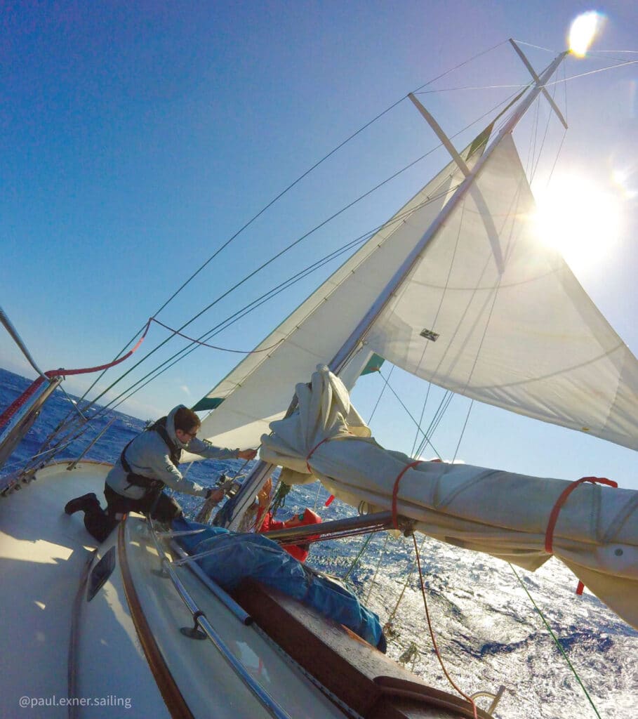 Sailboat heeled over with a storm trysail and headsail, sailing in heavy weather.