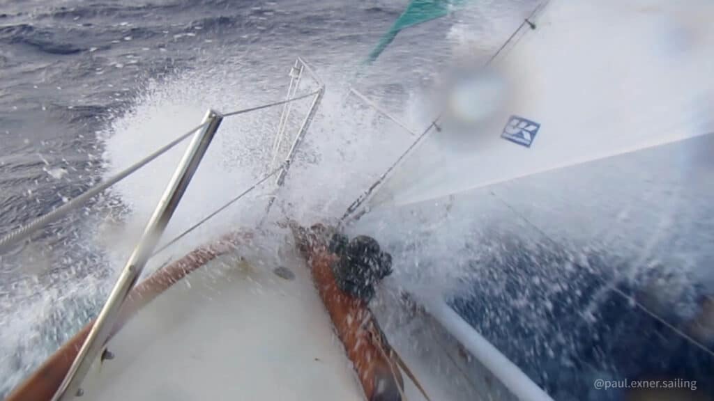 Photo shot from the foredeck of a boat overcoming wave resistance in heavy weather. Thee storm staysail is up and there is spray from the bow.