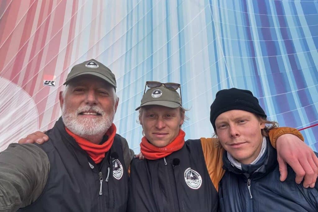 Expedition leader Keith Tuffley poses with ABEL TASMAN skipper, Isak Rockström, and first mate, Alex Rockström, in front of the Climate Stripes Gennaker. Photo Ⓒ Ocean Science Expedition.